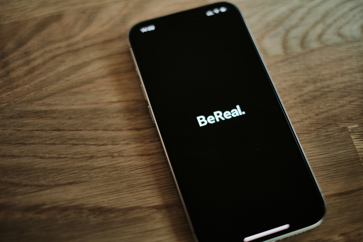 Ein Smartphone mit dem BeReal-Logo auf einem Holztisch.